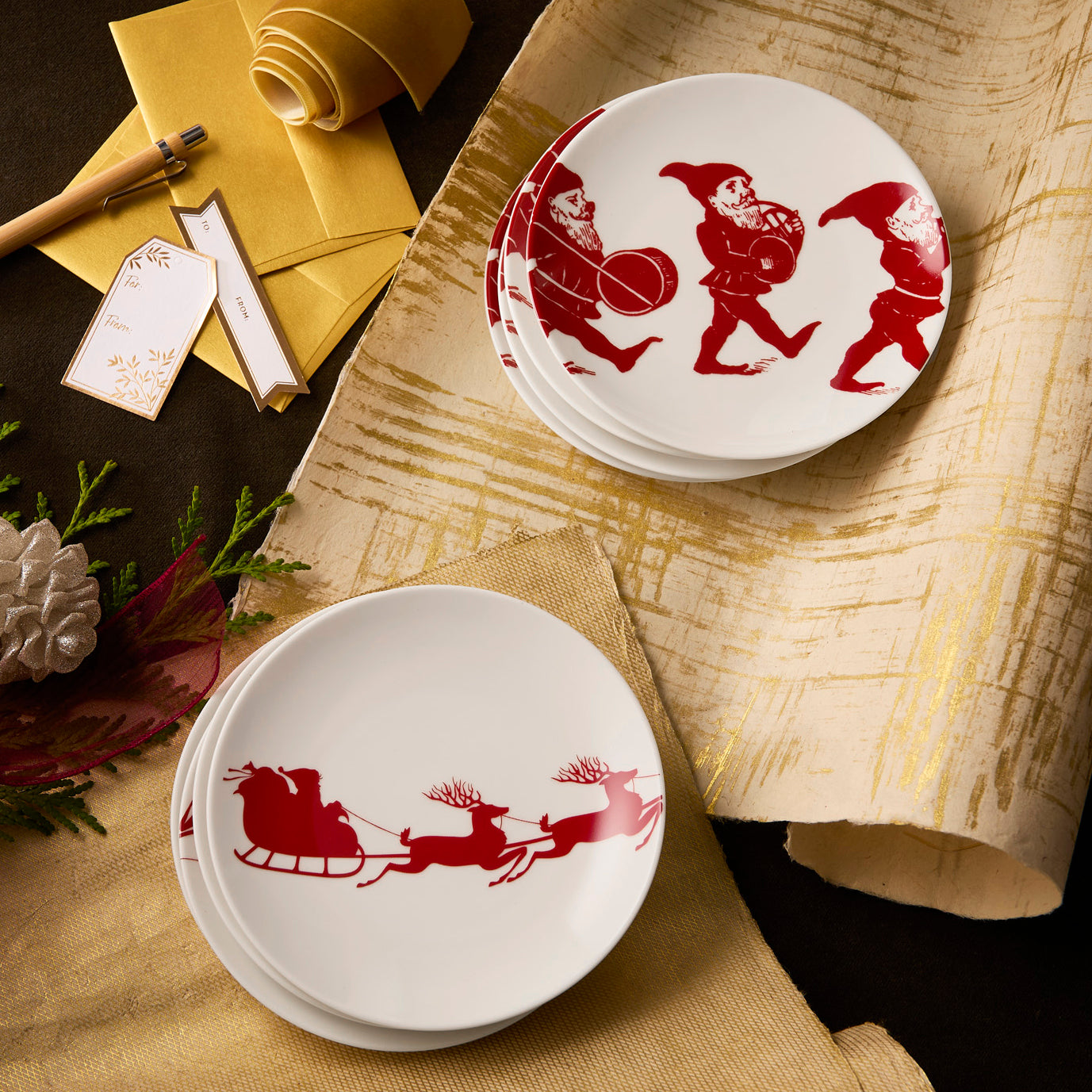 The "Santa's Sleigh" Bundle by Caskata features holiday porcelain plates with red elf and sleigh motifs, festive decor, ribbon, and gift tags—perfect additions to your holiday tableware collection.