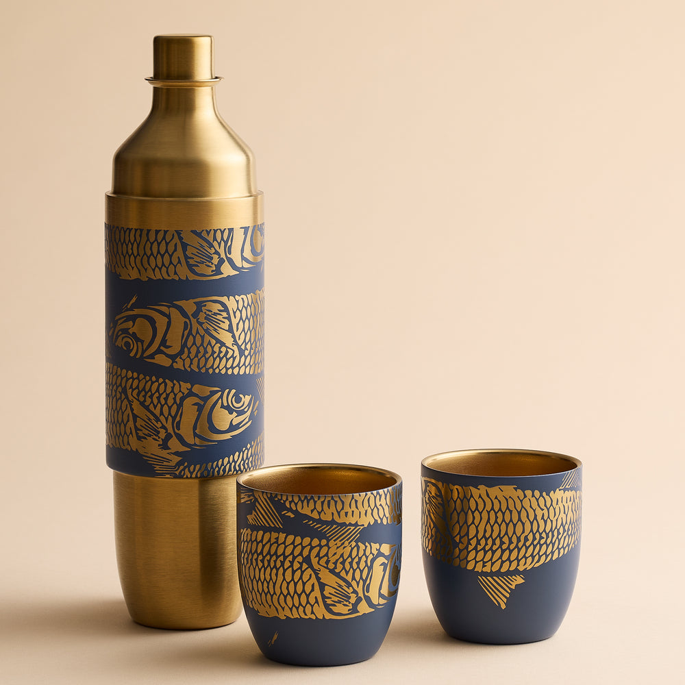 A gold-tone Caskata x High Camp Dark Blue Sardines Wine Flask and two matching magnetized tumblers, all decorated with a blue and gold pattern of swimming fish.