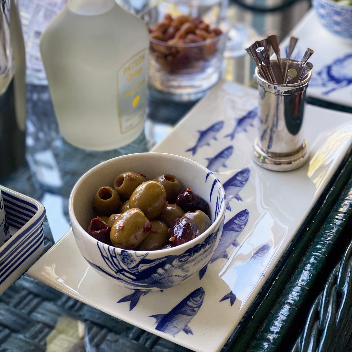 A Blue Crab Snack Bowl from Caskata holds seasoned olives on a nautically inspired bar cart.