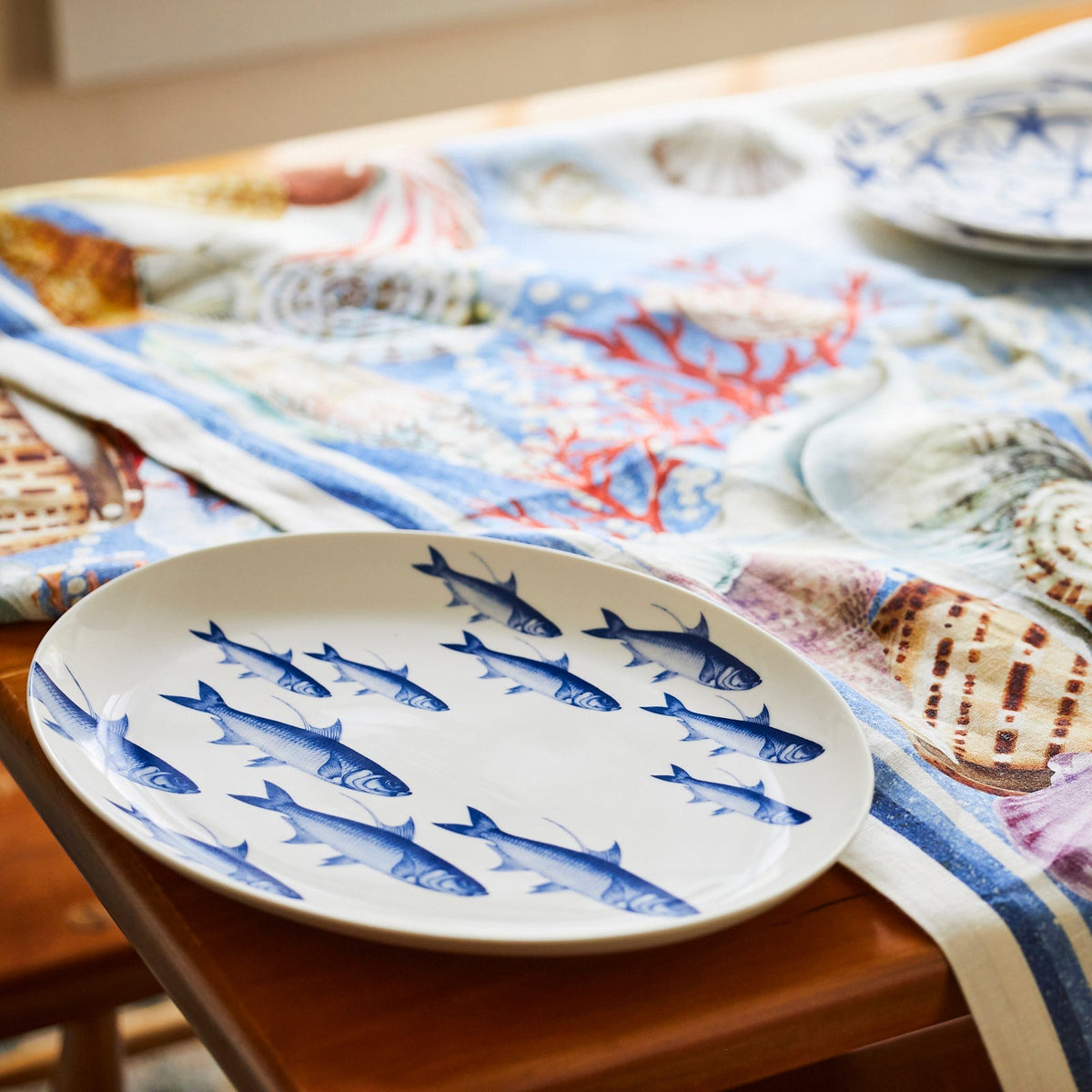 A Caskata Artisanal Home School of Fish Coupe Oval Platter sits on a table.