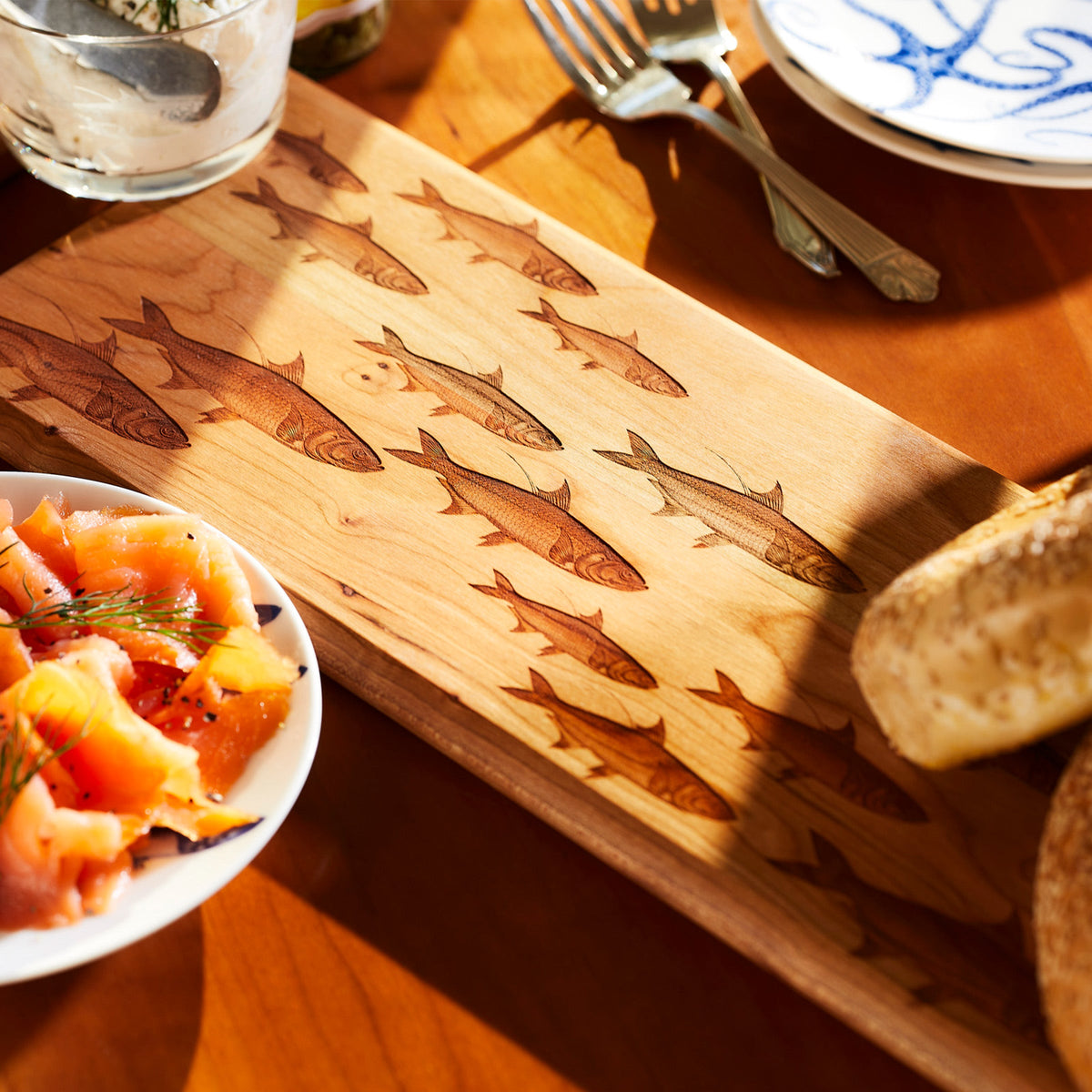 A Caskata School of Fish Serving Board with coastal charm, showcasing a delectable arrangement of salmon and bread.