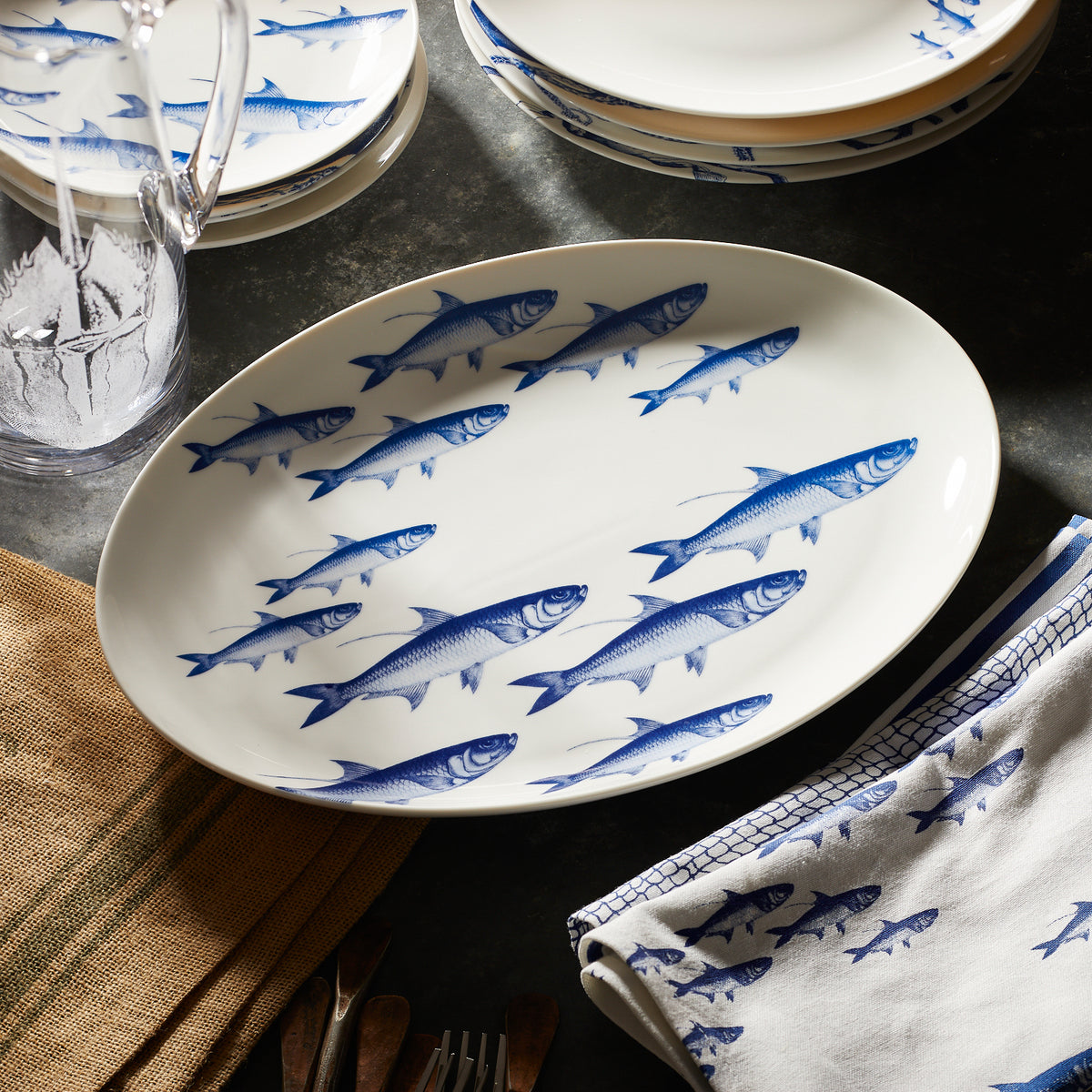 A blue and white porcelain platter with a School of Fish pattern on a zinc table from Caskata.