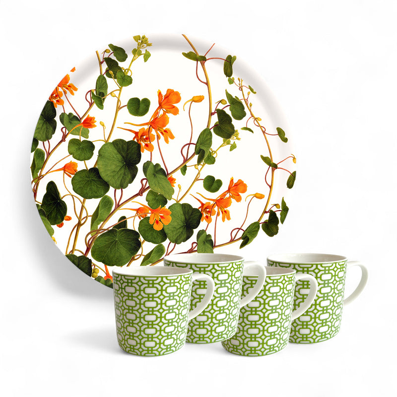 The Caskata "Serving Spring" Bundle features a round plate with an orange flower and green leaf pattern behind four porcelain mugs with green-and-white designs—a charming gift for gardeners.
