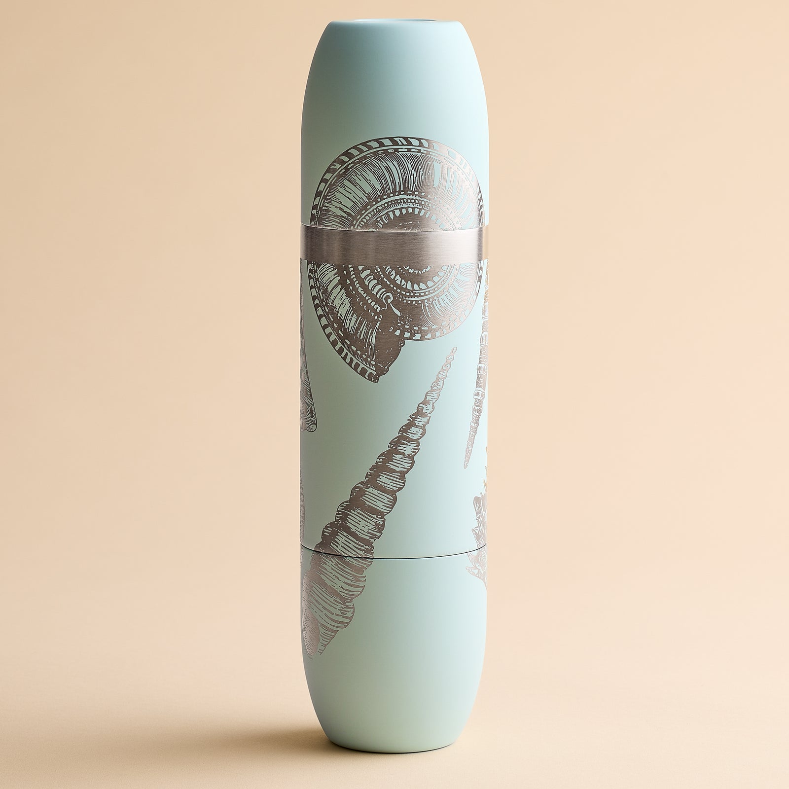 A Caskata x High Camp light blue cylindrical insulated wine flask featuring silver seashell illustrations on a beige background.