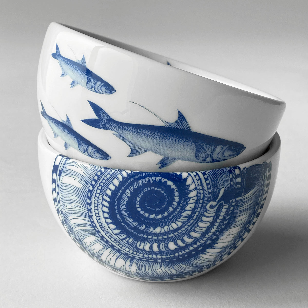 Two blue and white School of Fish Snack Bowls with a school of fish on them by Caskata Artisanal Home.