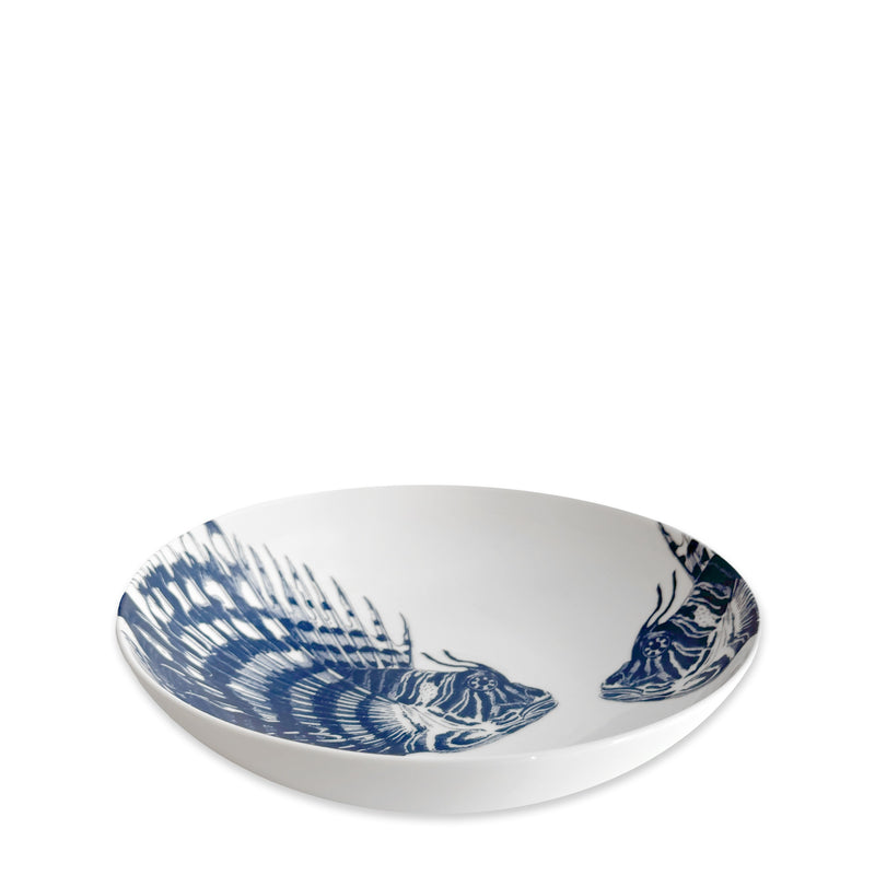 The Caskata Spiky Fish Entrée Bowl is a white shallow bowl with two blue fish illustrations inside, perfect coastal dinnerware for adding a fresh maritime touch.