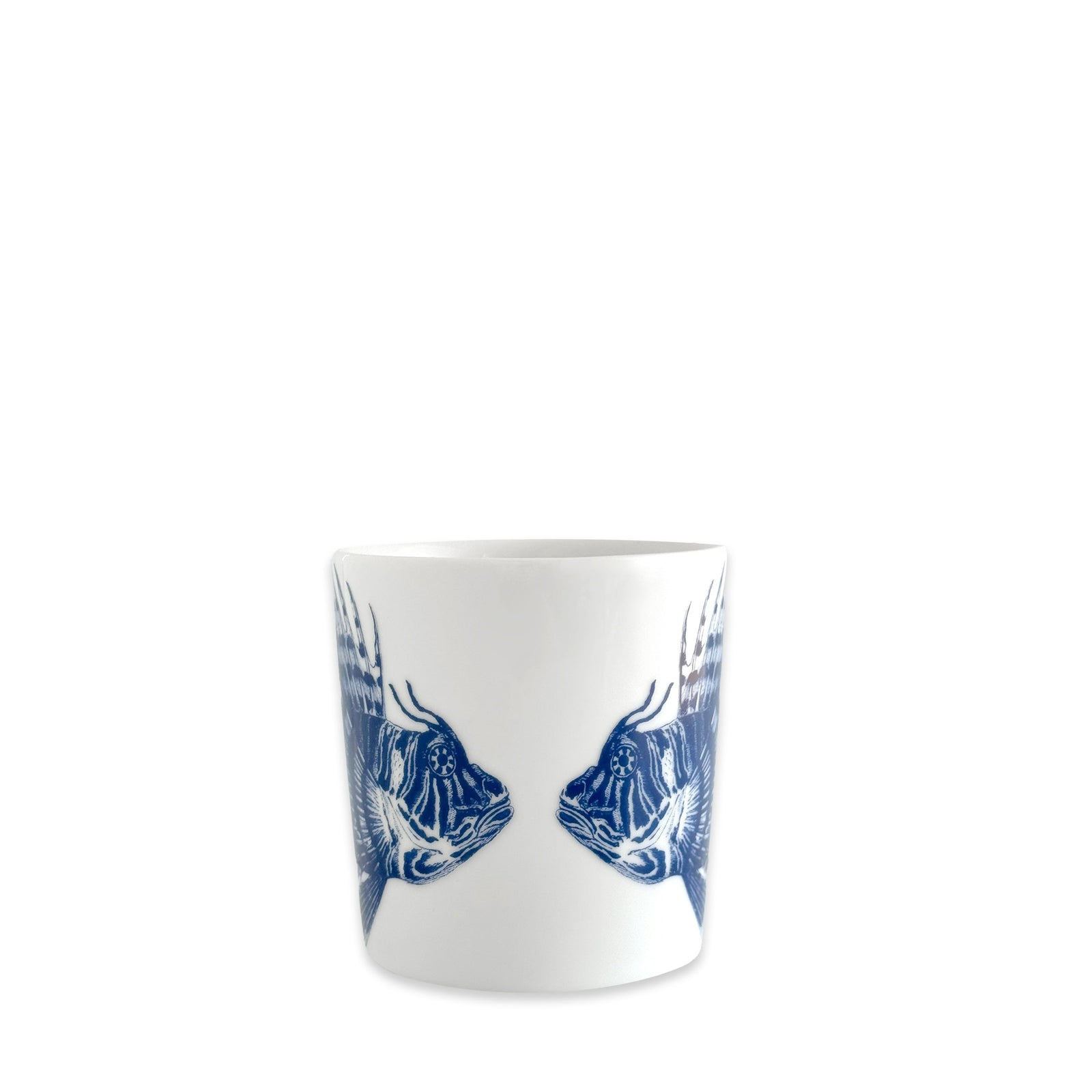 The Caskata Spiky Fish Mug is a white ceramic cup with two blue fish illustrations facing each other, recalling classic blue and white porcelain styles—ideal for bringing coastal charm to your tableware collection. Shown on a plain white background.