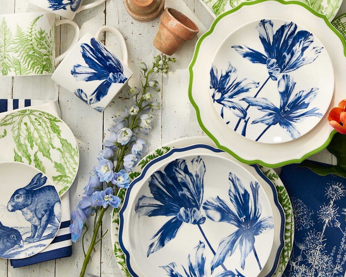 A set of plates and cups featuring the Caskata Tulip Entrée Bowl, ideal for elegant gatherings.