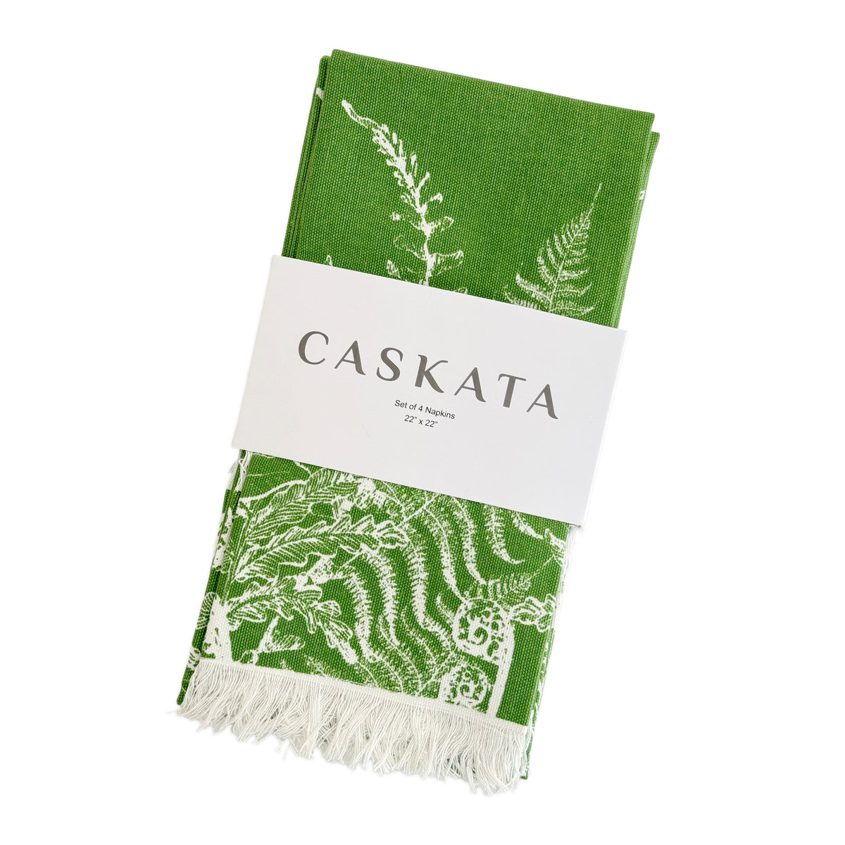 A folded green fern napkin with white botanical designs and fringe, wrapped in a band labeled "Caskata Spring Verde Dinner Napkins Set of 4, 22” x 22”—perfect for spring table decor.
