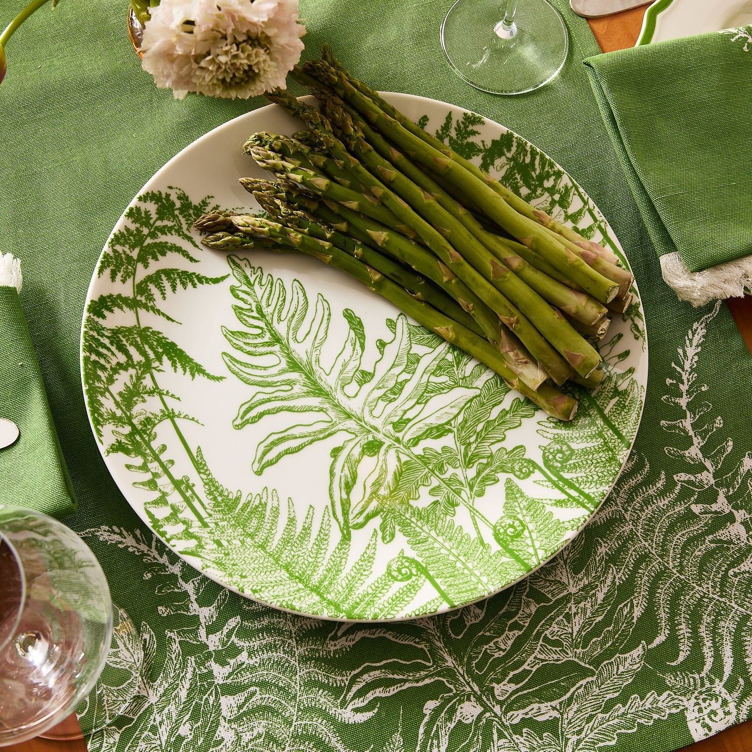 The Caskata Spring Verde Round Platter is a premium porcelain serving dish adorned with detailed green fern illustrations on its round white surface.