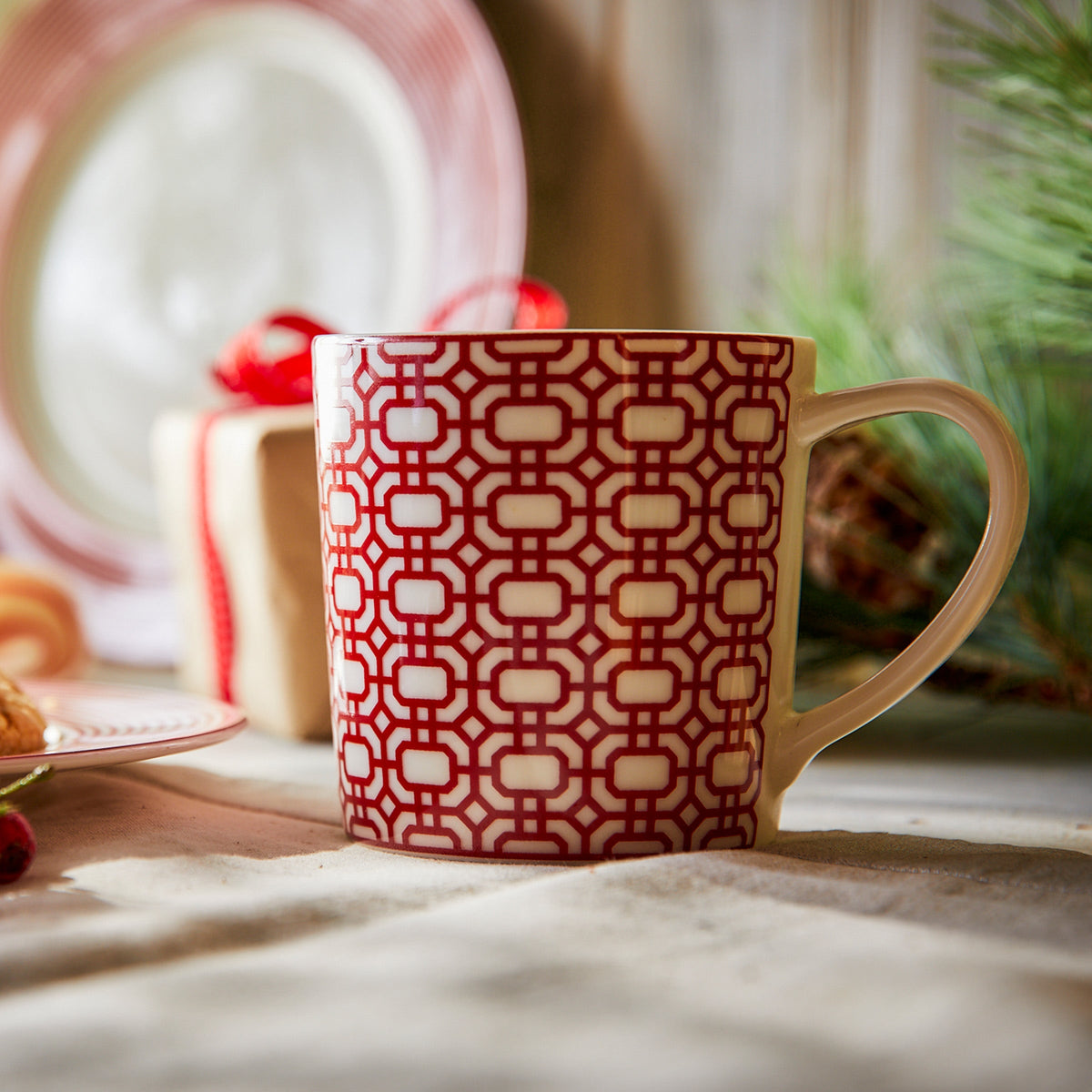 A Newport Garden Gate Crimson Mug and plate made of high fired porcelain on a table. (Brand Name: Caskata Artisanal Home)