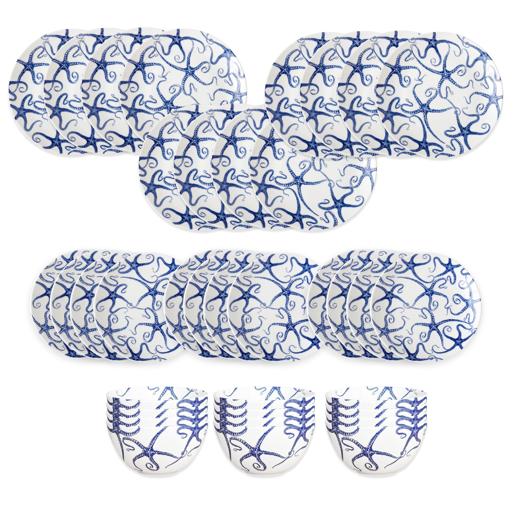 The Caskata Starfish Table for 12 set features oval and round white plates plus three bowls, all adorned with intricate blue swirled patterns like blue and white porcelain, arranged in rows on a white background.