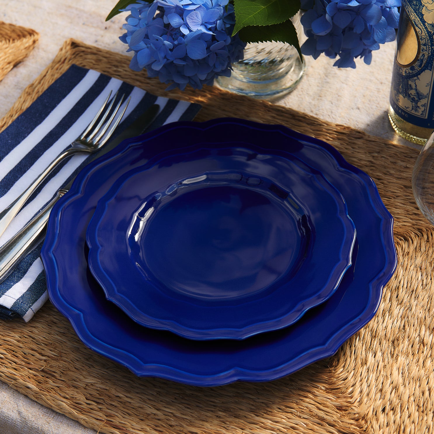 A solid dark blue Caskata Stella Scalloped Solid Blue Salad Plate with a scalloped edge.