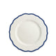 A top-view of the Stella Scalloped Blue Salad Plate by Caskata, featuring white porcelain with a scalloped edge and dark blue trim, evokes the charm of vintage dinnerware.