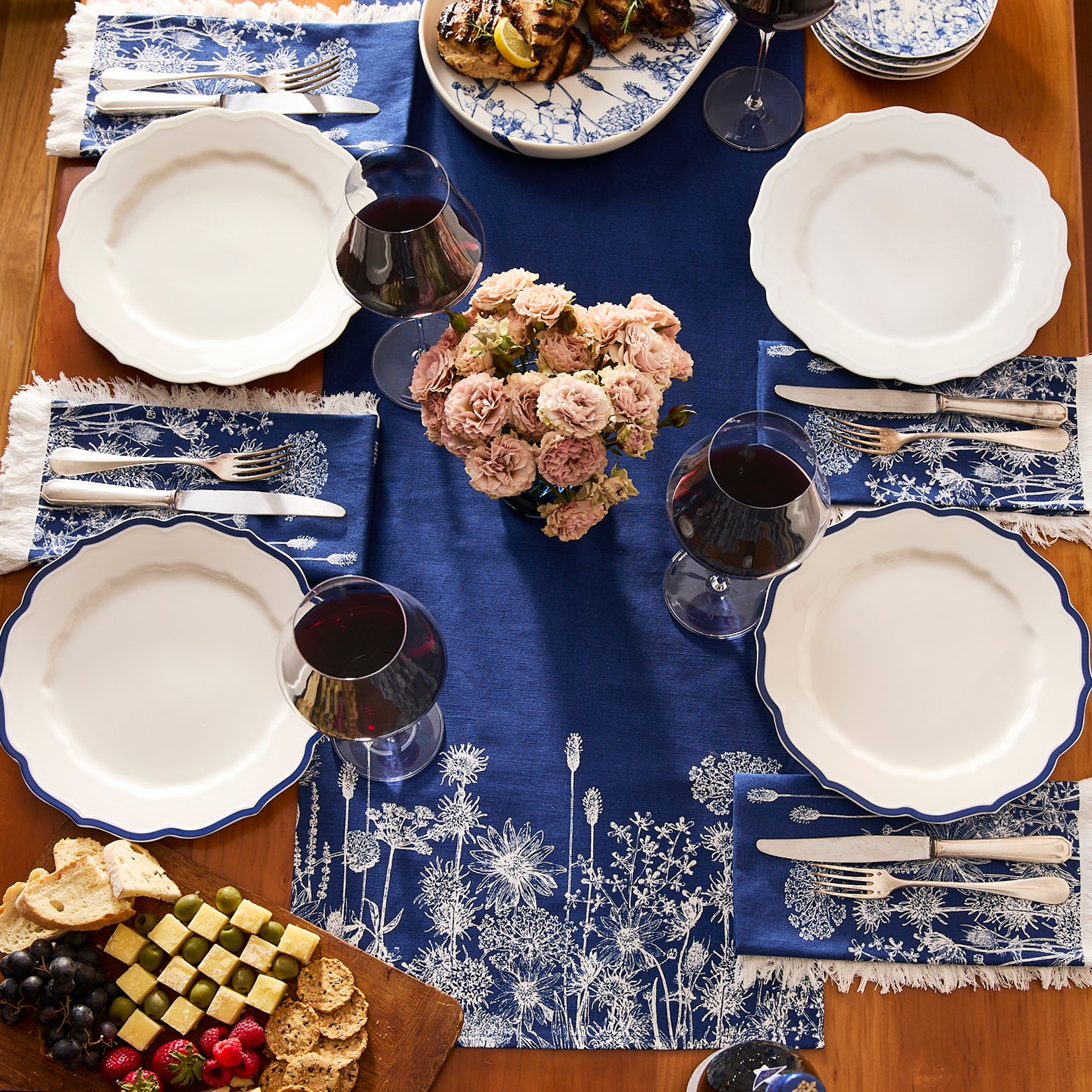 Two folded navy blue cotton table runners with white botanical prints, each wrapped in a "Caskata Summer Blues Table Runner" label—a charming addition to cottage-core or summer decor.