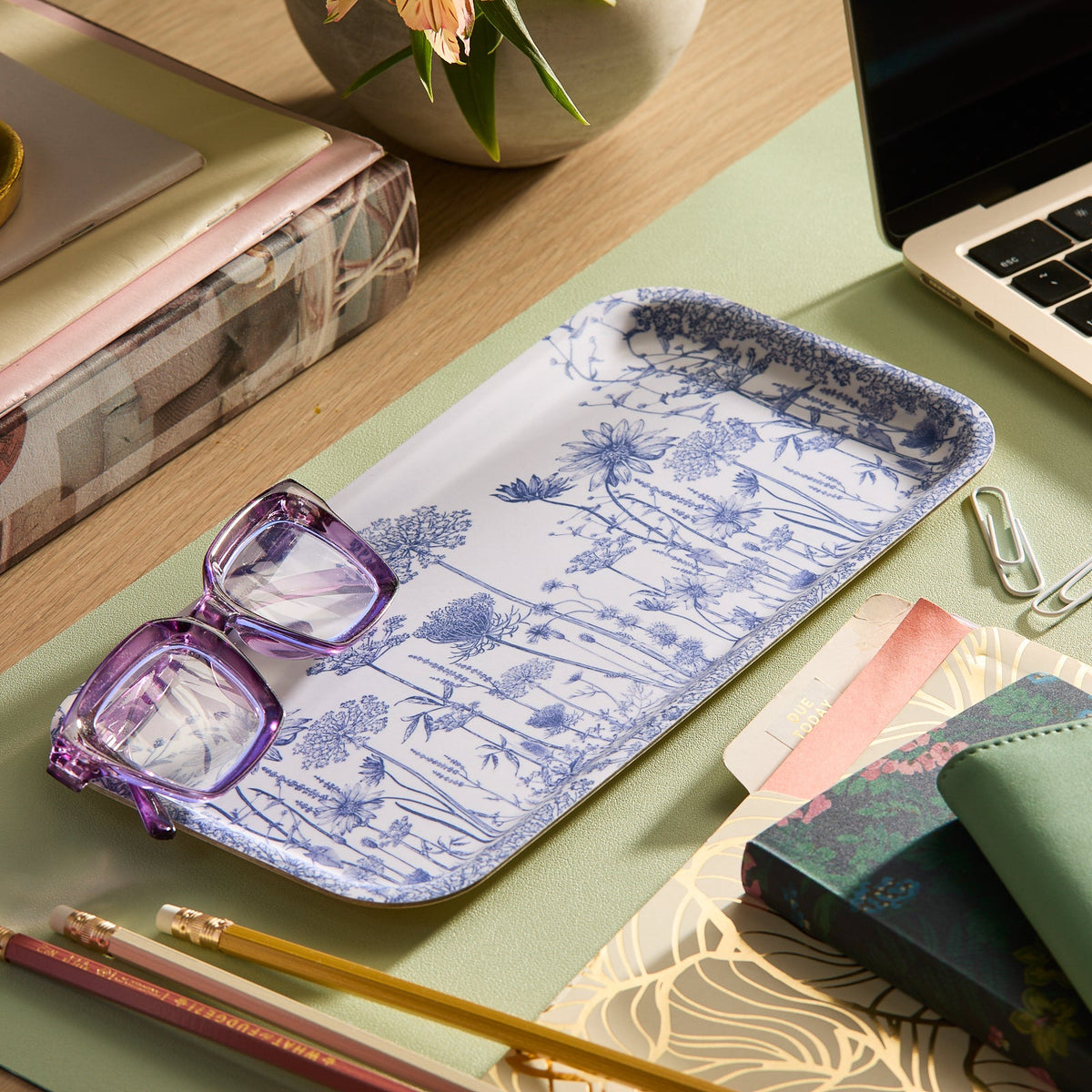 The Caskata "Blooming Blues" Bundle features a birchwood tray with a blue floral design and two purple glasses—an ideal cottage-core desk gift for organizing books, a laptop, pencils, and paperclips.