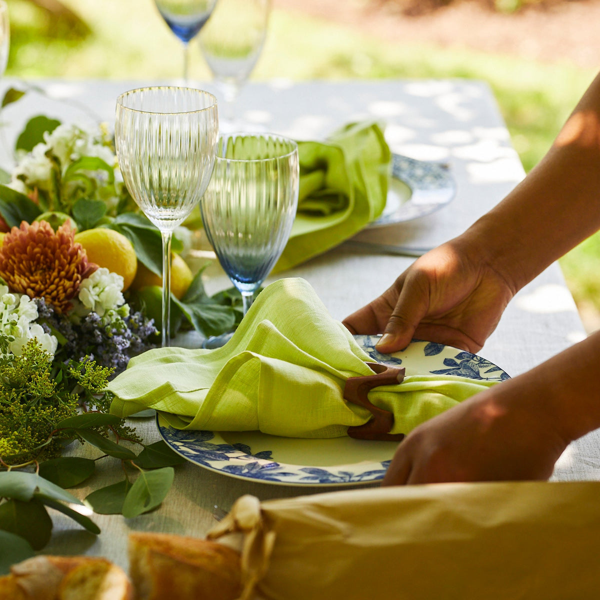 A person placing a Dot and Army Wooden Zigzag Napkin Rings Set/4 on a bohemian table.