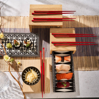 Sushi and sashimi are elegantly served on Caskata's Marrakech Petite Serving Tray with red chopsticks, set on a wooden table adorned with bone china for a touch of Art Deco flair.