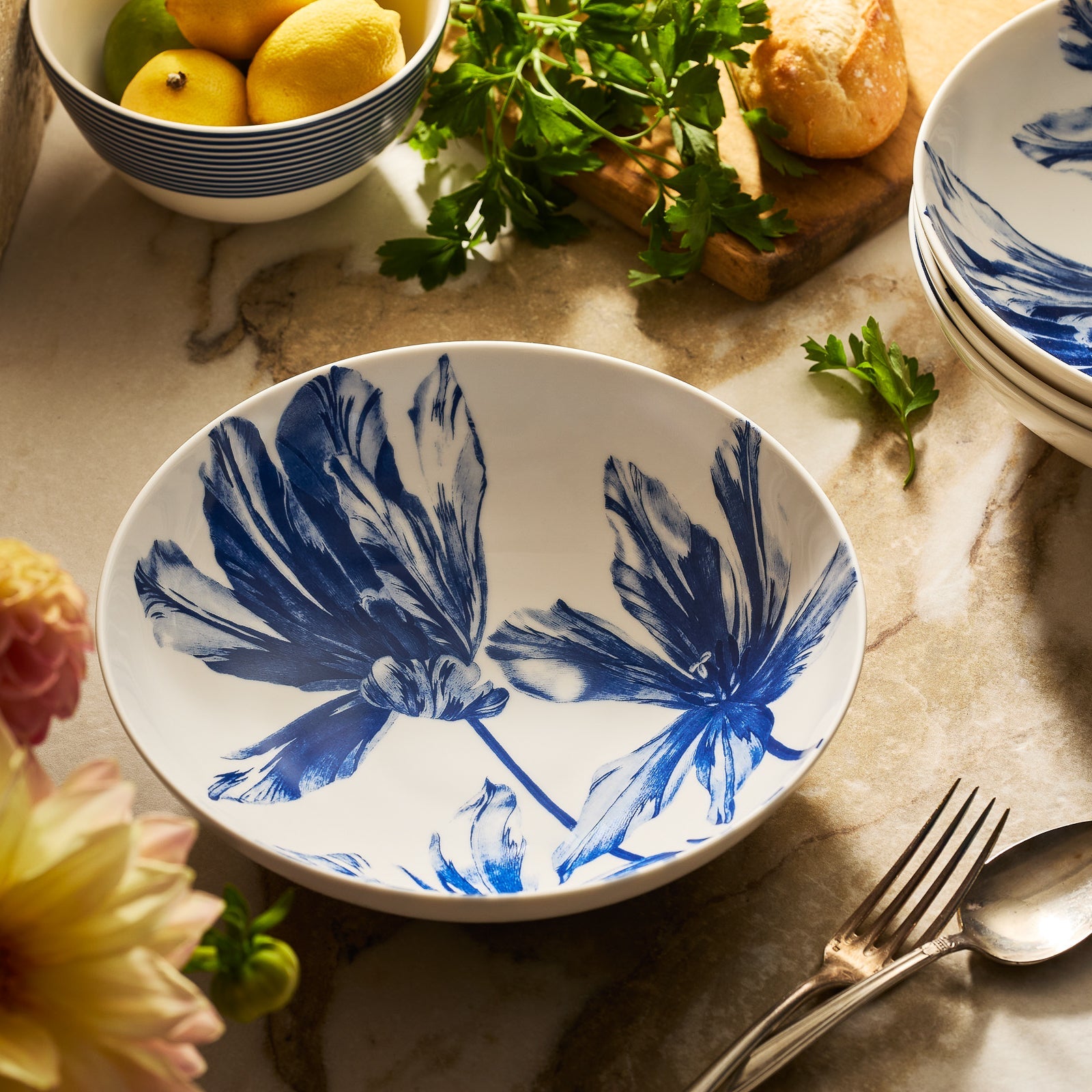 The Caskata Tulip Entrée Bowl features a blue and white porcelain design, bringing elegant charm to any table setting.