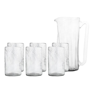 The Viento Essentials Serving Bundle by Caskata features a clear handblown glass pitcher with handle and six matching glass tumblers, shown on a plain white background.