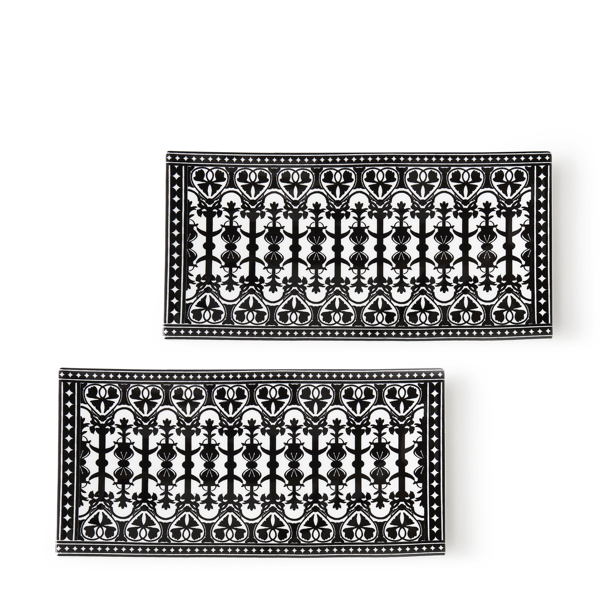 Two rectangular bone china trays with intricate black-and-white ornamental patterns, featuring symmetrical designs of hearts, swirls, and geometric shapes. These hand-decorated Casablanca Medium Sushi Trays, Set of 2 by Caskata add elegance to any table setting.