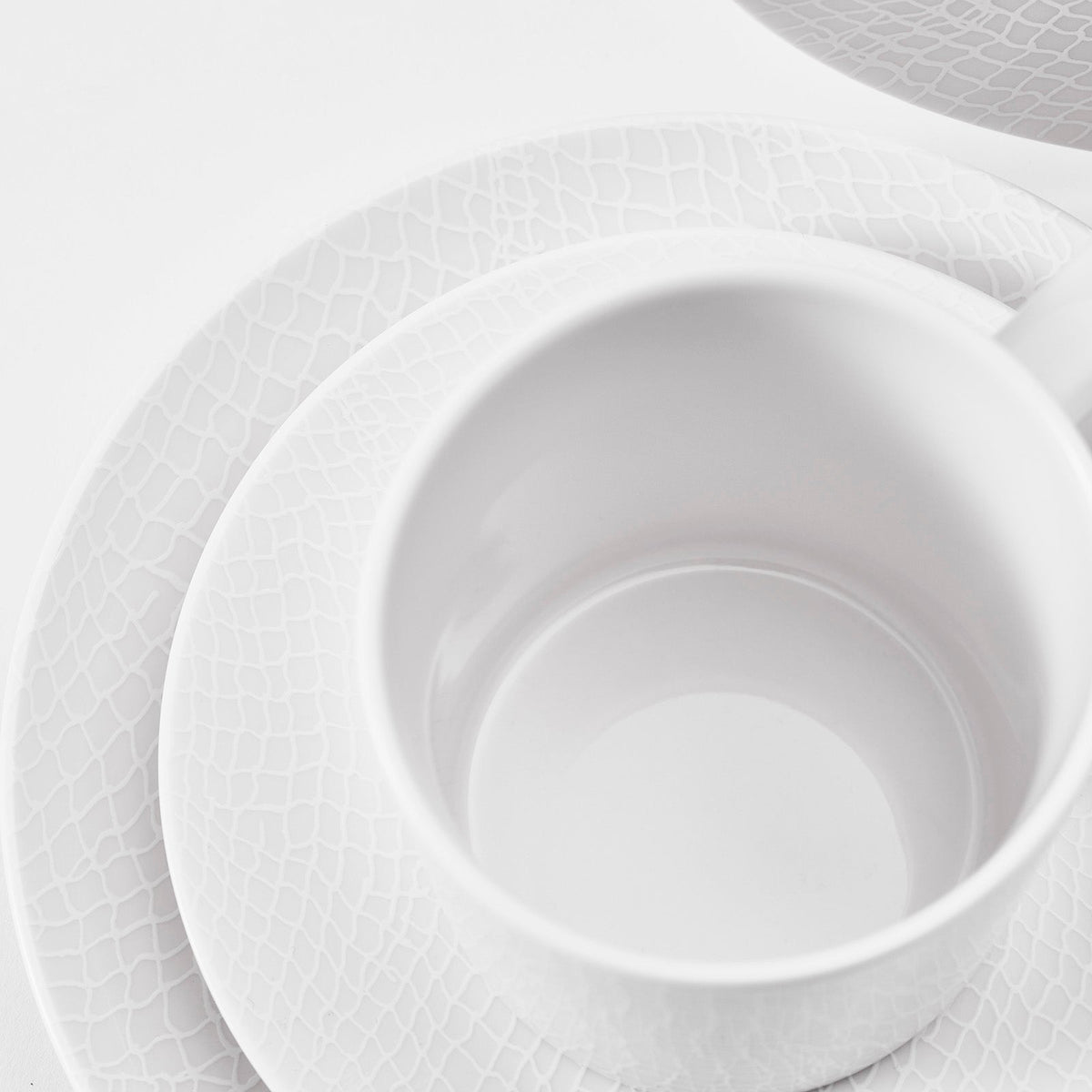 Closeup of mug, bread and salad plates in Catch pattern 16 piece dinnerware set from Caskata 