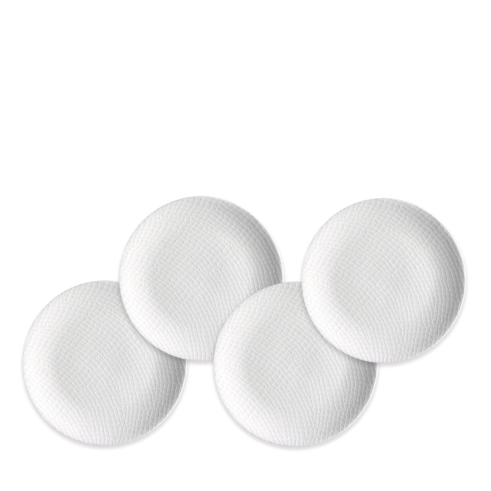 Four round, textured, white Catch Small Plates from Caskata Artisanal Home are arranged in a slightly overlapping pattern against a plain background, reminiscent of small plates caught in a fisherman's net.