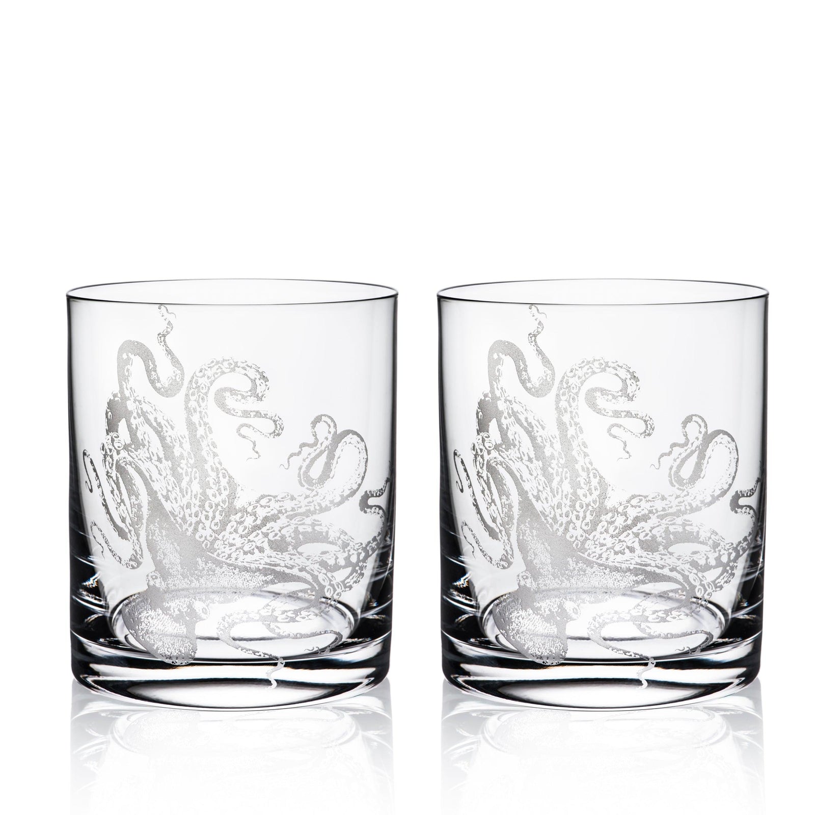 Two Lucy Rocks Glasses, crafted from exquisite crystal glassware by Caskata Artisanal Home, feature intricate octopus designs created using the sand-etching technique. Placed side by side, they merge elegance with a touch of marine mystique.