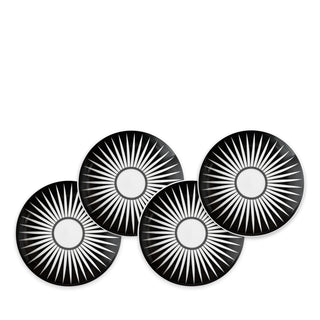 Four Marrakech Small Plates by Caskata Artisanal Home, each made of high-fired porcelain with white radial starburst patterns, are arranged in a staggered overlapping formation reminiscent of Marrakech's intricate designs.