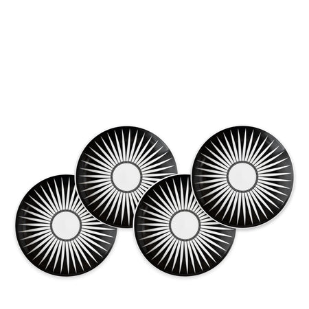 Four Marrakech Small Plates by Caskata Artisanal Home, each made of high-fired porcelain with white radial starburst patterns, are arranged in a staggered overlapping formation reminiscent of Marrakech's intricate designs.