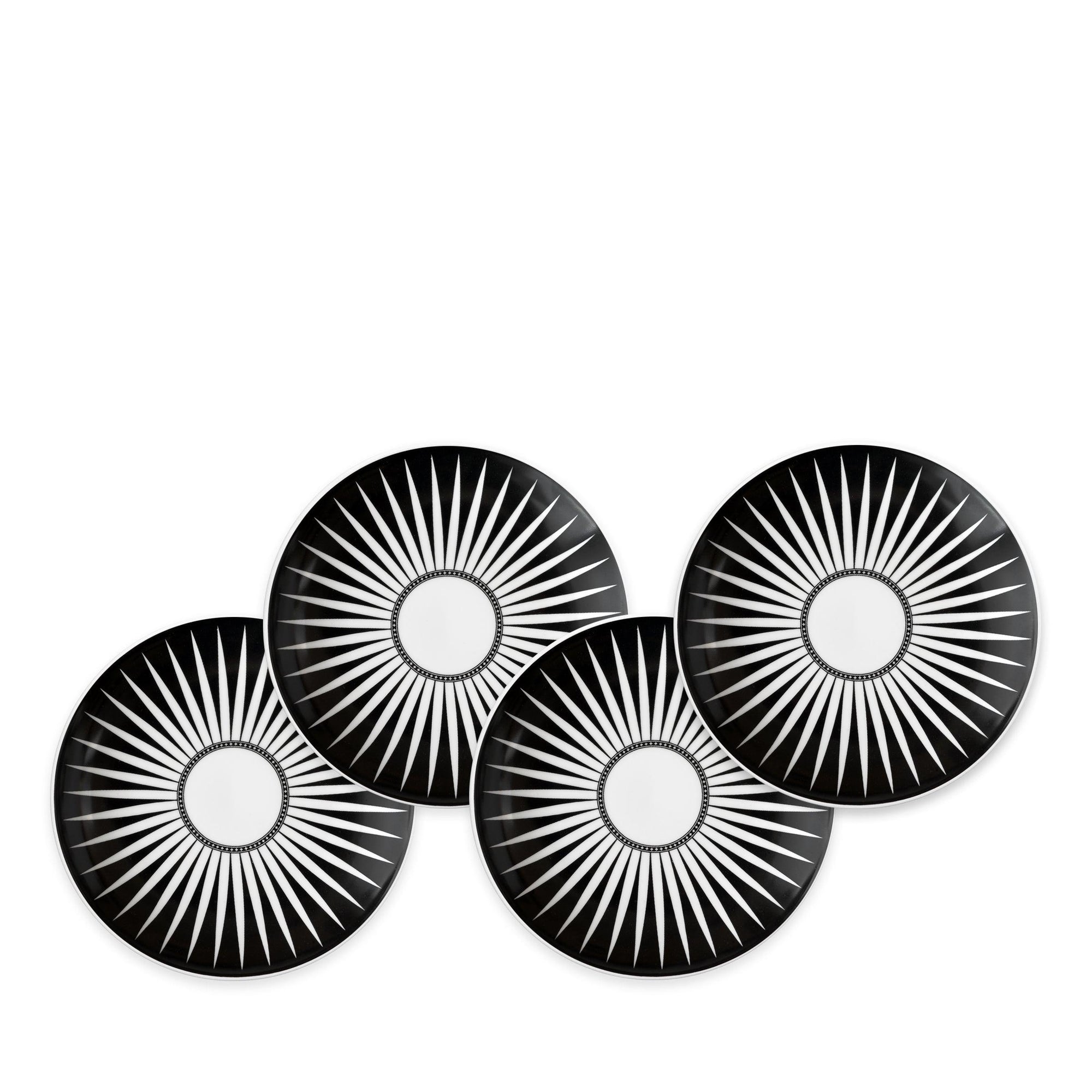 Four Marrakech Small Plates by Caskata Artisanal Home, each made of high-fired porcelain with white radial starburst patterns, are arranged in a staggered overlapping formation reminiscent of Marrakech's intricate designs.