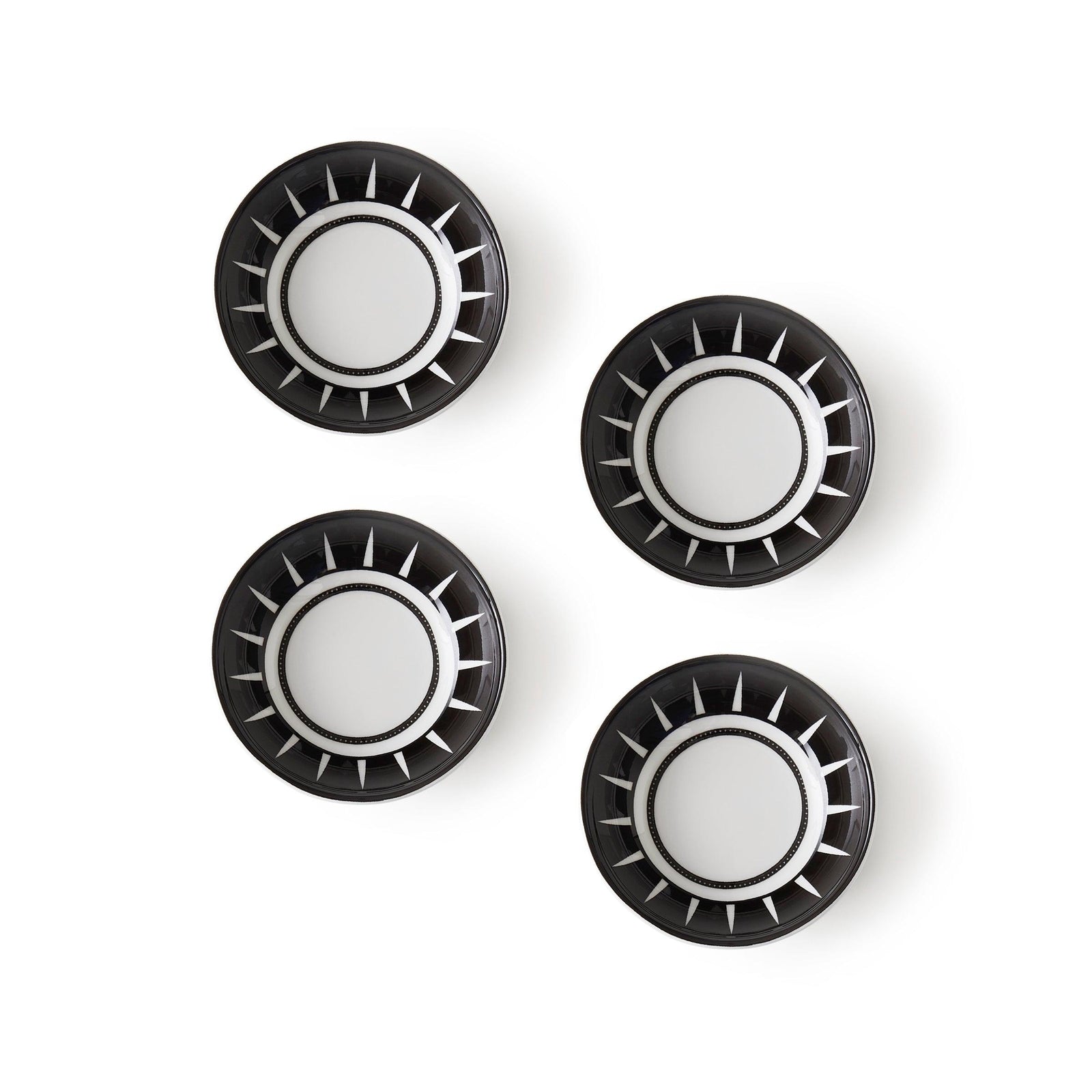 Four black and white plates, designed in a Moroccan-inspired pattern, are arranged in a grid on a plain white background. Each plate features circular designs with radial stripes. These are the Marrakech Dipping Dishes, Set of 4 by Caskata.