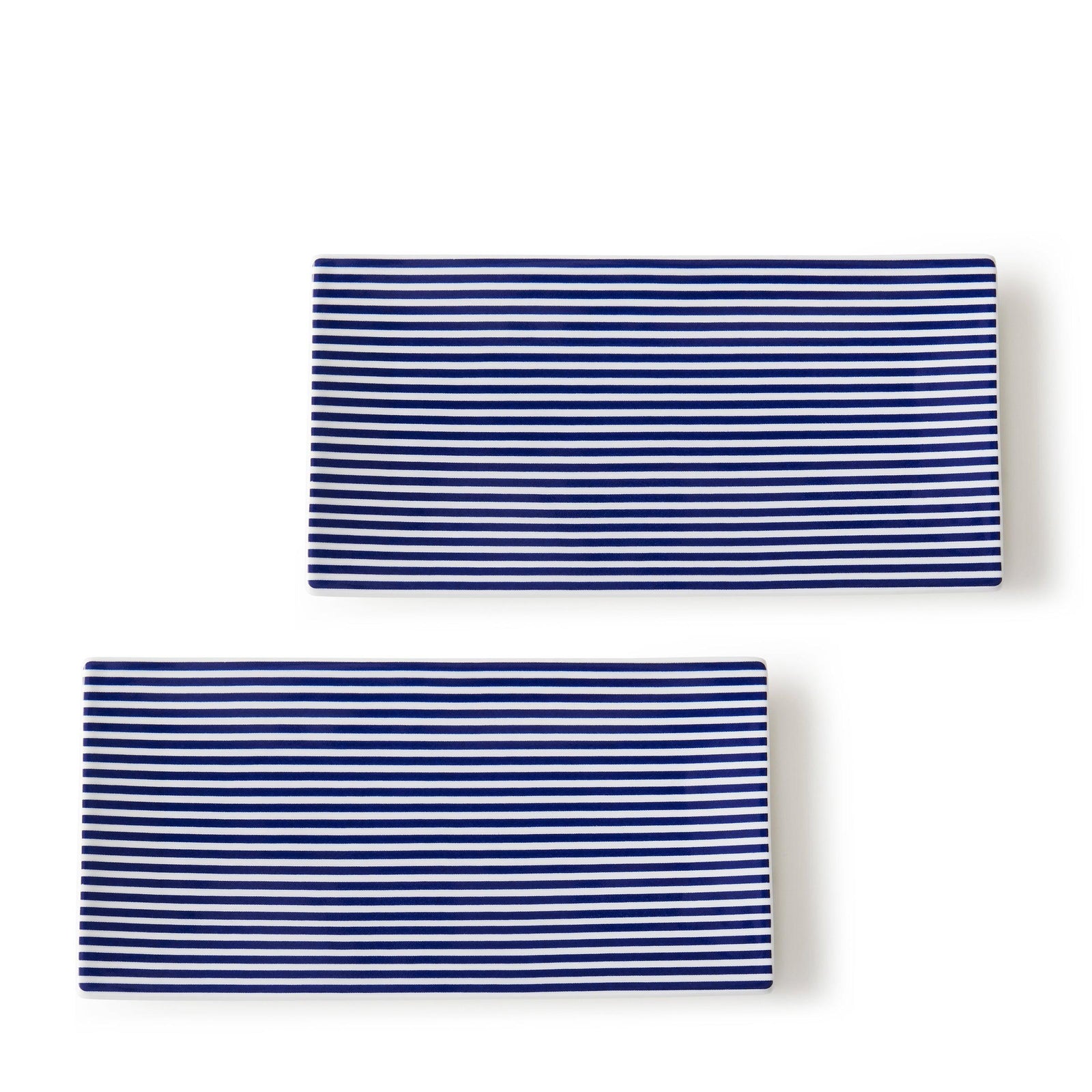The Newport Petite Trays by Caskata adorn the pristine white background with causal elegance, their rectangular bone china bodies showcasing a blue and white horizontal design arranged in parallel.